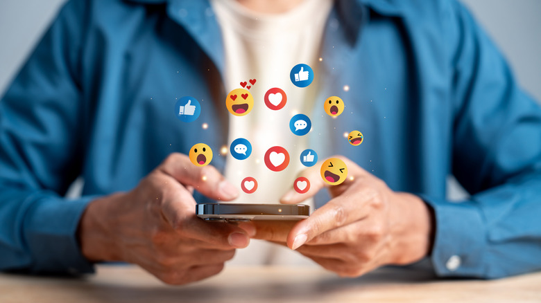 A number of emoji popping out of the screen of a smartphone