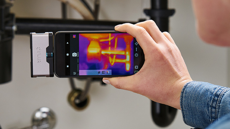 Hand holding Flir One connected to phone detecting plumbing