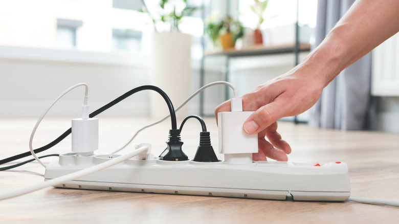 A person plugging devices into a power strip.
