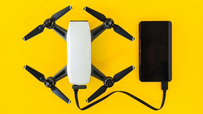 drone plugged into charging using a power bank against a yellow background