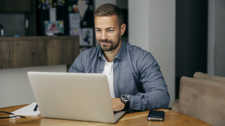 A man using a laptop in a modern home setting.