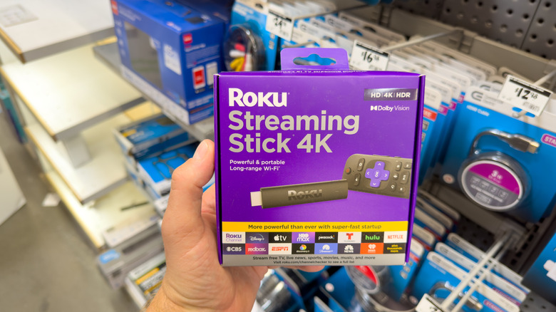 A person holding the box of the Roku Streaming Stick 4K.