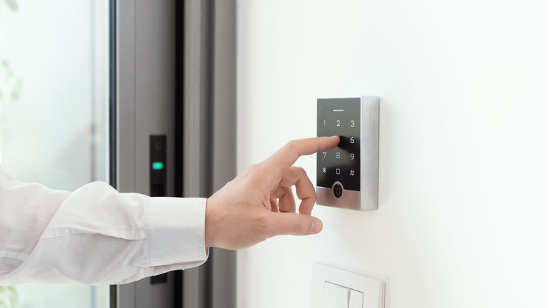 A man setting an alarm code for a security system.