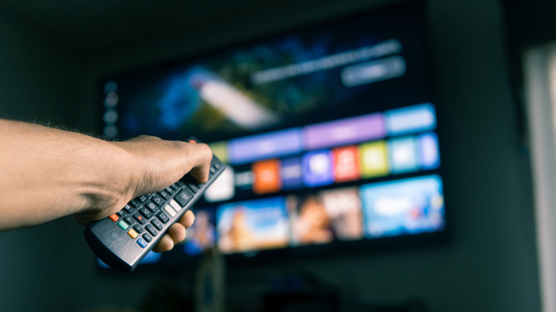 Hand holding a remote control, browsing streaming services on a smart TV.