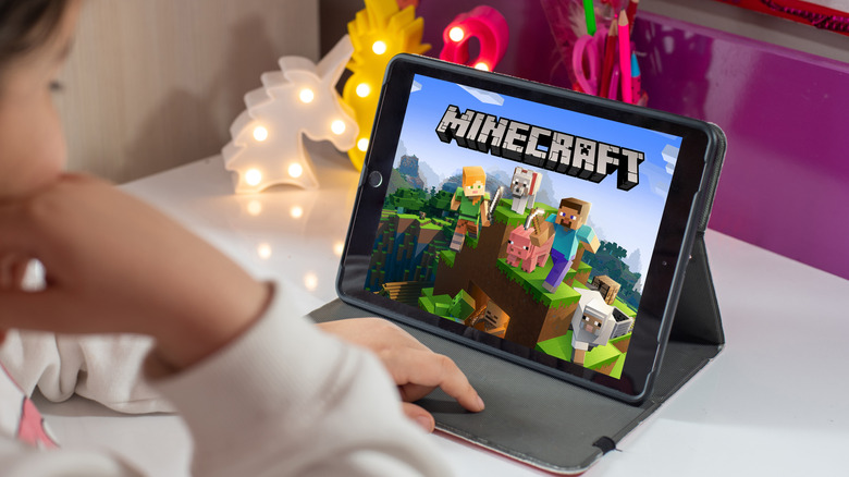 Minecraft app spashscreen, featuring the game's logo, on an ipad used by a child