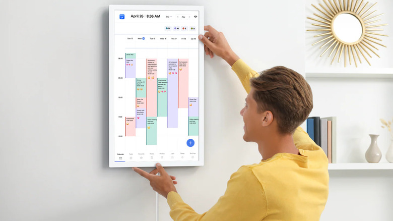 Man hanging portrait digital calendar on wall