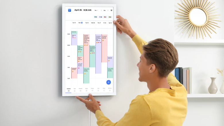 Man hanging portrait digital calendar on wall