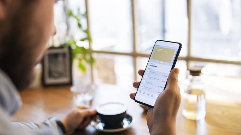 A person at a coffee shop managing funds with a digital wallet