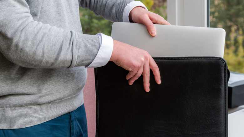 A man putting a laptop inside a laptop bag.
