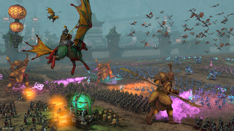 Total War: Warhammer 3 battle scene with armies, monsters, and flying units clashing on a large battlefield.