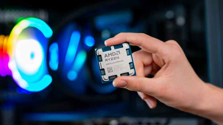 AMD Ryzen 9 9950X3D processor held in front of an RGB-lit gaming PC.