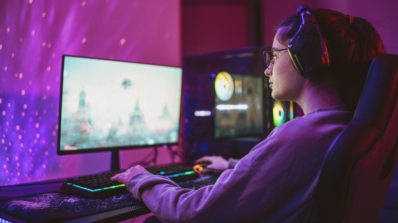 Person wearing a headset while gaming at a neon-lit desktop setup.