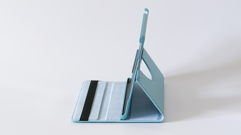 Light blue tablet folio case propped up as a stand on a white surface.