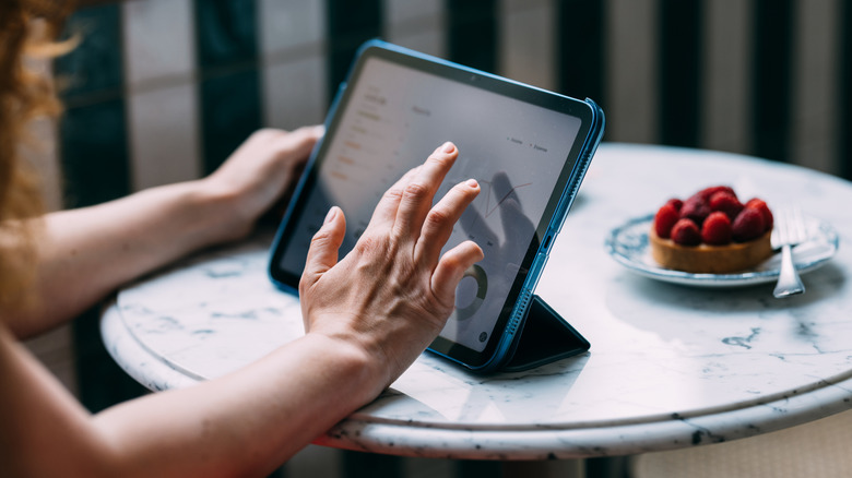 Person using a tablet in a case at a marble table.