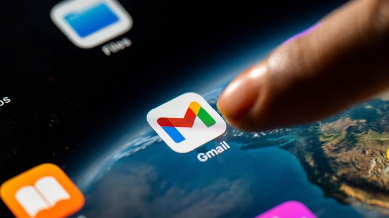 Finger about to tap the Gmail app icon on a tablet screen.