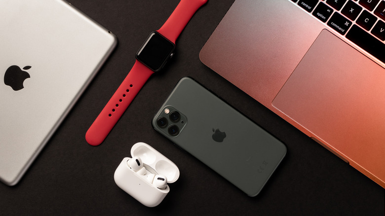 An iPad, AirPods, Apple Watch, iPhone, and MacBook placed against a dark background