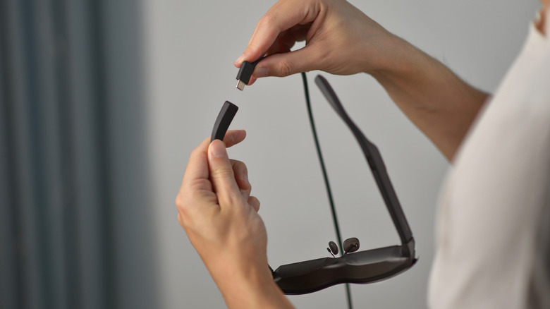 A person plugging a USB-C cable into smart AR glasses.