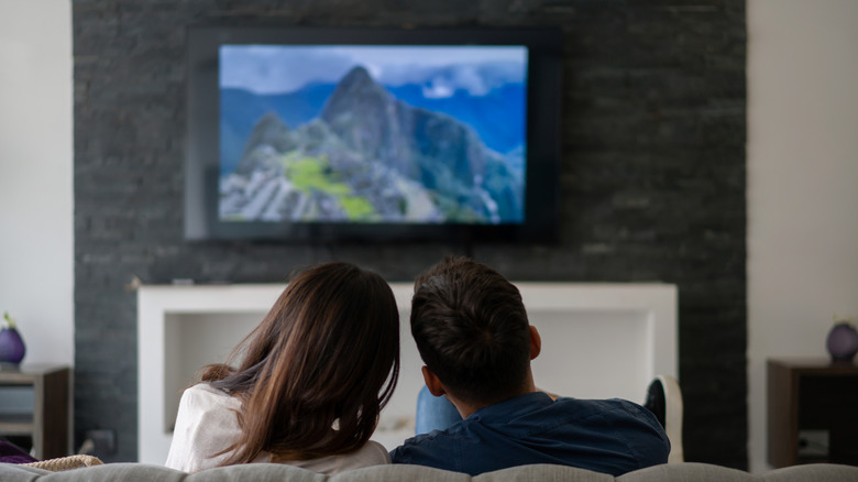 two people watching wall-mounted tv