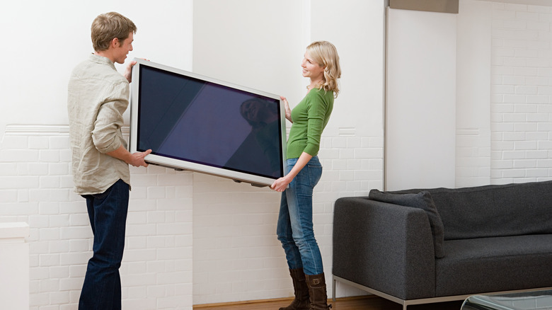 people moving a tv in living room