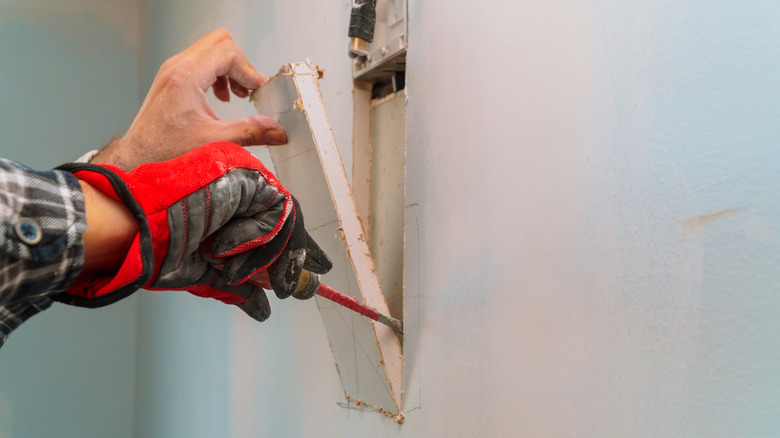 person cutting hole in sheetrock