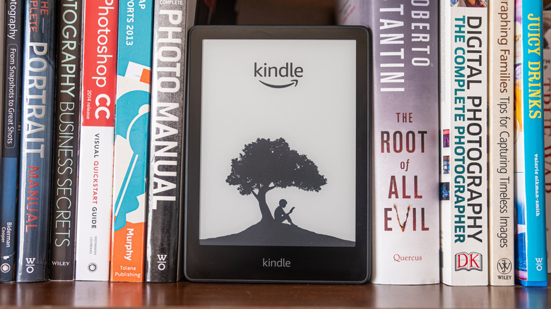 A Kindle on a bookshelf alongside physical books on both sides
