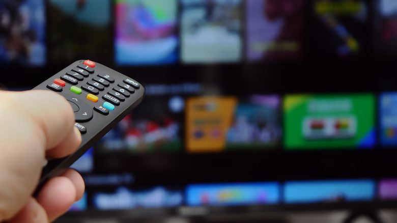 Hand pointing TV remote at smart TV streaming service interface