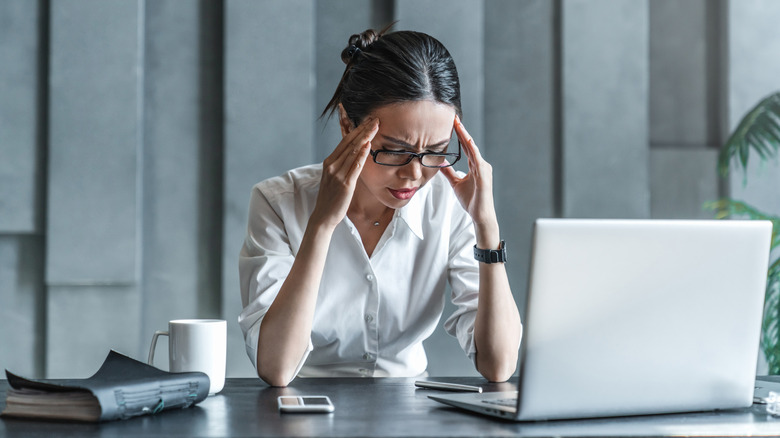 Young woman working on laptop having headache