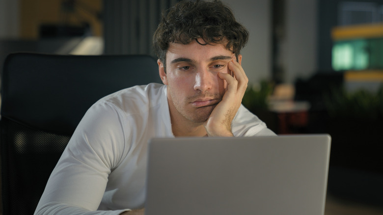 Tired businessman working on laptop