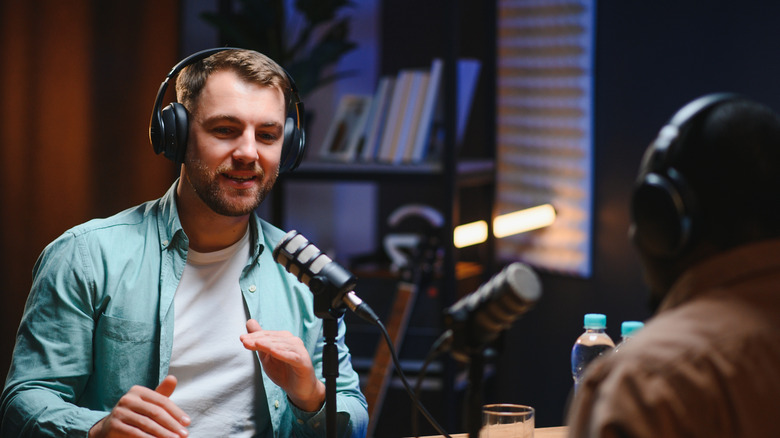 Two people recording a podcast with mics in front of them