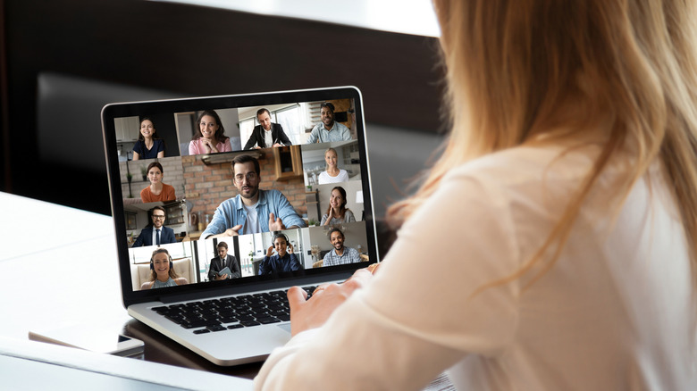 Woman participating in a group video conference on a laptop.