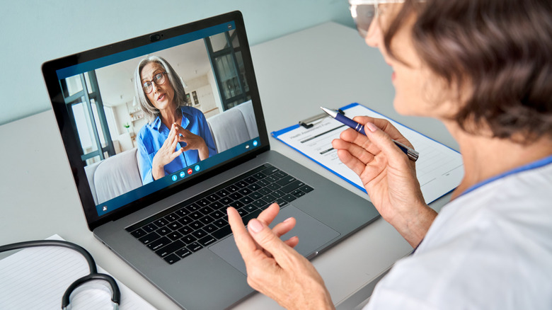 Healthcare professional conducting a virtual consultation with a patient on a laptop.