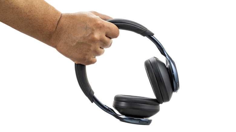 A person holding a pair of headphones
