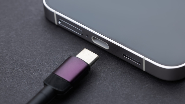 Close up view of a phone's USB-C charging port with a charging cable lying near it