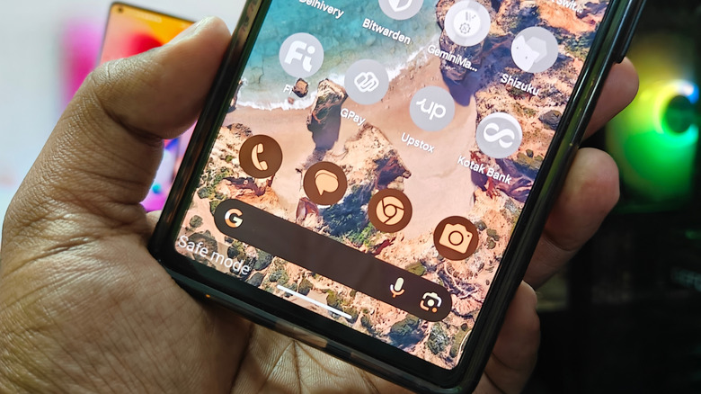 Someone holding a phone with a "Safe mode" overlay shown on the lower left side of its screen