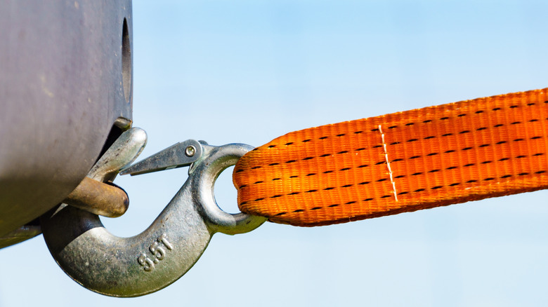 A tow hook and strap attached to a car.
