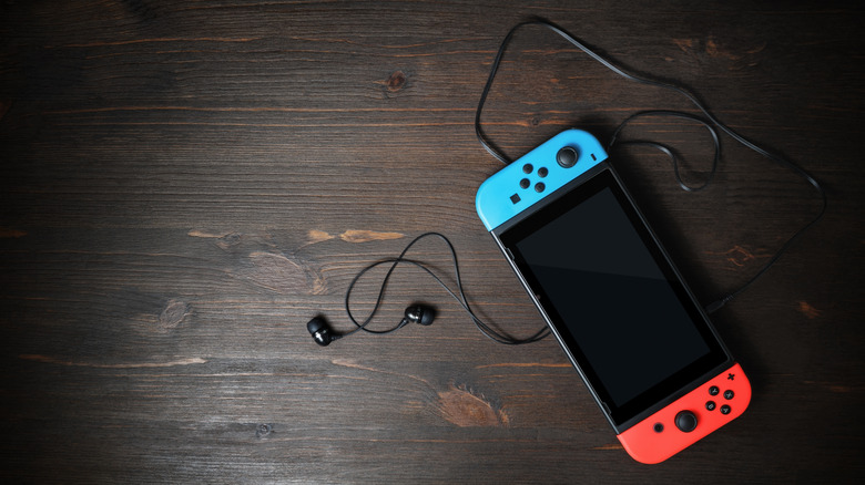 An original Nintendo Switch on a table with earphones attached
