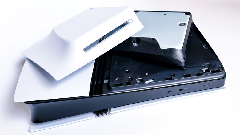 A PS5 Slim with a cover removed and the optical drive out in the open