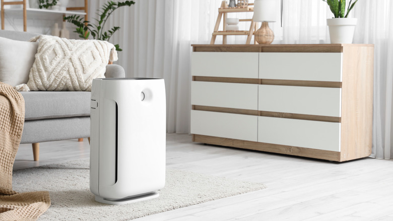 A white air purifier placed inside a living room