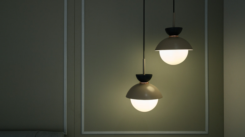 Two hanging lamps with a green wall in the background