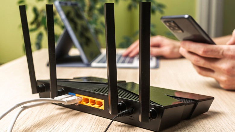 A Wi-Fi router placed on a workstation with a person working on a laptop