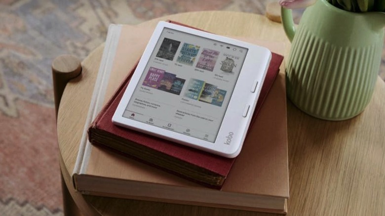 The Kobo Libra Colour e-reader on top of a pile of books.