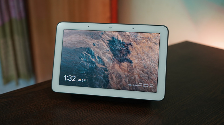 Smart display showing the time and weather on a dark wooden table.