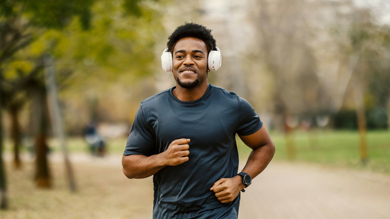 A person with headphones on jogging outside while wearing a smartwatch