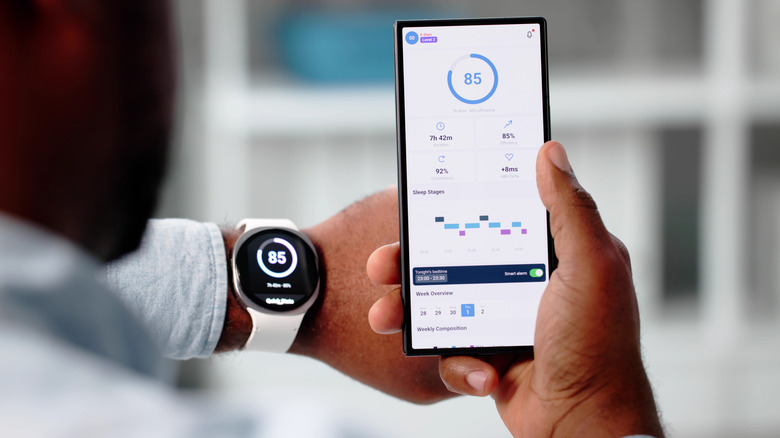 A person holding their smartphone against their smartwatch to look at synced data