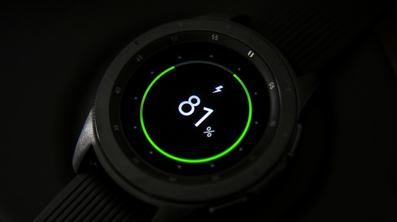 A smartwatch being charged and displaying the charging status