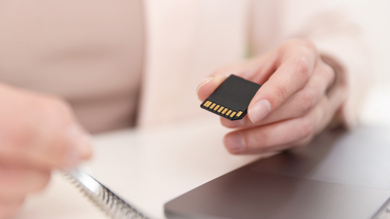 person holding SD card near laptop