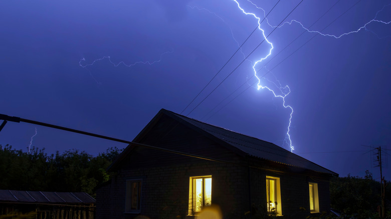 Lightning striking over a house during a thunderstorm.