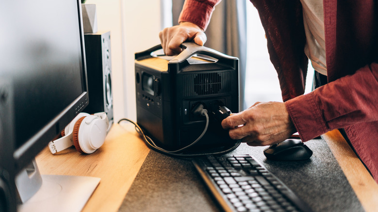 A person plugging computer components into an uninterruptible power supply.