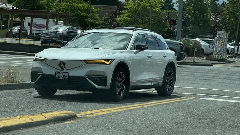 2025 white Acura ZDX driving through an intersection.