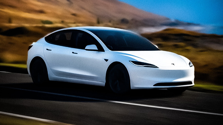 Tesla Model 3 in white driving through a desert.